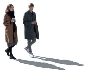 two backlit women with coffee cups walking