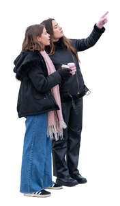 two young women with coffee cups standing and pointing at smth