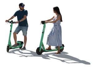 two backlit people with electric scooters standing