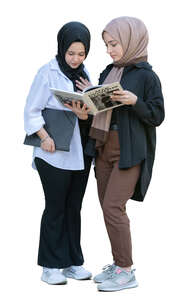 two muslim girls standing and reading a book