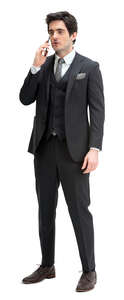 man in a black suit standing and talking on a phone