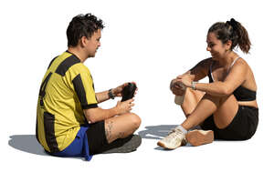 man and woman sitting on the ground and resting after workout