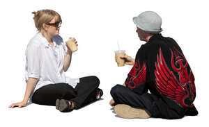 man and woman sitting outside on the ground and drinking coffee