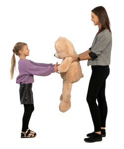 woman handing a little girl a big toy bear