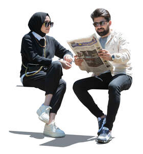 man and woman sitting and reading newspaper