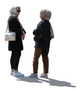 two backlit young muslim women standing and talking
