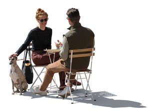 backlit man and woman and a dog sitting in a cafe