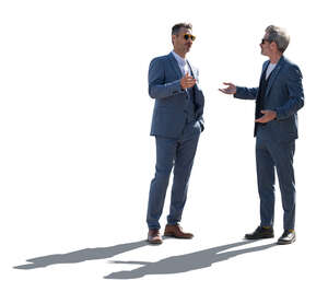 two backlit men in suits standing and talking