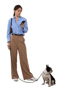 woman with a dog standing and looking at a phone