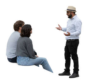 man standing and talking to two people sitting