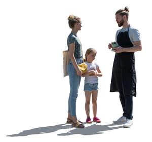 backlit woman with her daughter talking to a man working at a market