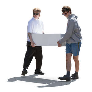 two backlit young men carrying a large box