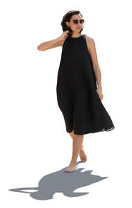 backlit woman in a black dress walking barefoot