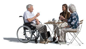 older man in a wheelvhair sitting in a cafe with family