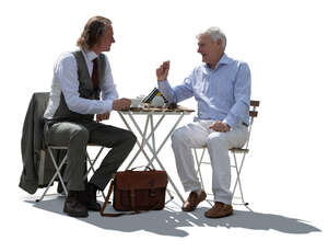 two backlit men sitting in a cafe