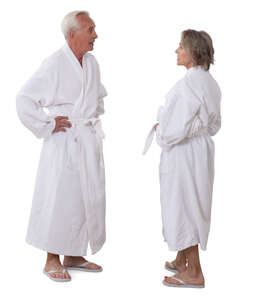 senior man and woman in white bathrobes standing and talking
