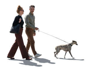 backlit man and woman walking with a dog