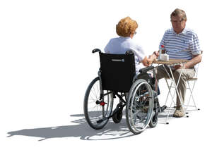 backlit couple with a woman in a wheelchair sitting in a cafe