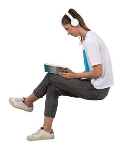 woman with headphones sitting and reading a book