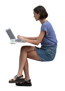 woman sitting at a  table and working with computer and drinking coffee