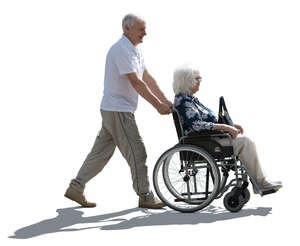 backlit man pushing a woman in a wheelchair