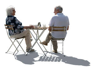 backlit senior couple sitting in a street cafe