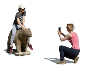 woman taking a picture of her friend posing with a statue