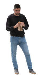 man standing and eating a sandwich