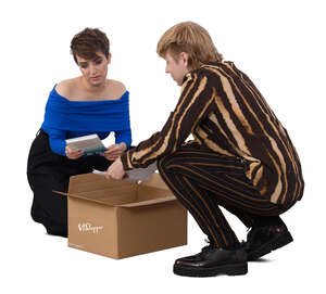 two people squatting and taking books out from a box