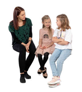 woman sitting and talking to two girls