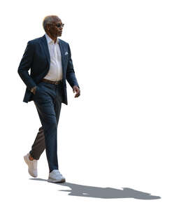 backlit black man in a grey suit walking