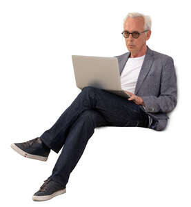 older gentleman sitting on a sofa with laptop