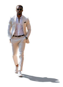 backlit black man in a white suit walking