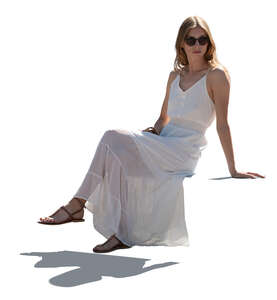 backlit woman in a white summer dress sitting