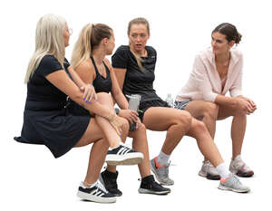 four sporty women sitting and talking after workout