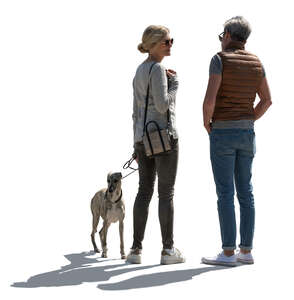 backlit man and woman with a dog standing and talking