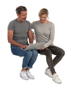 man and woman sitting and looking at laptop together