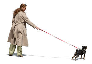 woman wearing a trenchcoat walking a dog