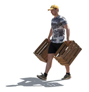 backlit man carrying wooden crates