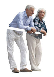 two elderly people standing up on a balcony and leaning on a railing