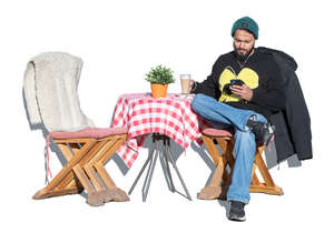 man sitting in an outdoor cafe on a sunny winter day