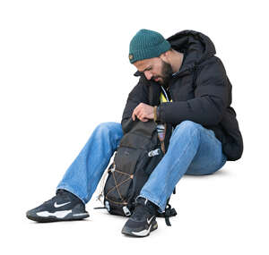 cut out man sitting and taking smth from his backpack