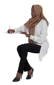 cut out muslim woman sitting behind the desk and writing