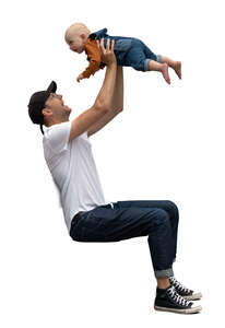 man sitting holding a baby up in the air 