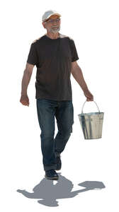 cut out backlit older man carrying a bucket