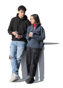 two people leaning against the wall and drinking coffee