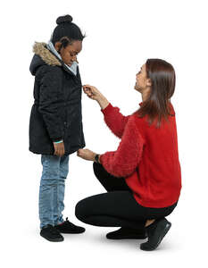 woman helping a little girl put on her coat