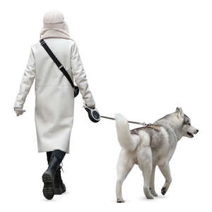 woman in a white overcoat walking a dog
