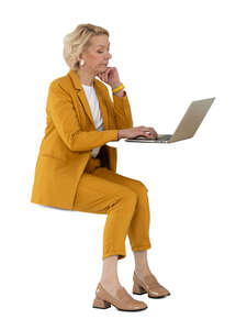 cut out woman in a yellow suit sitting and working with laptop