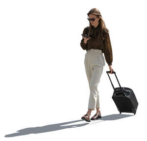backlit woman with a suitcase walking and texting
